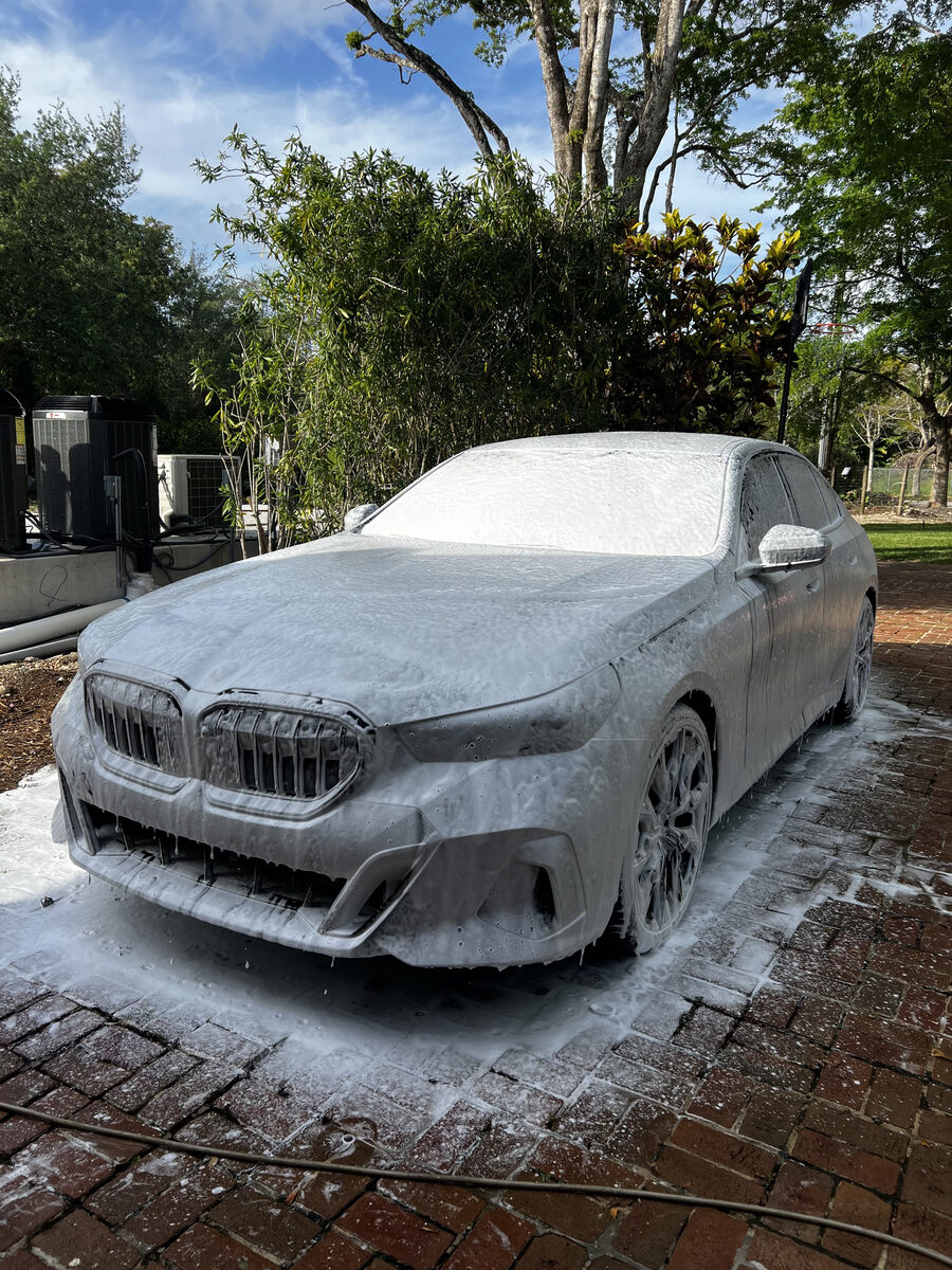 BMW 5 Series covered in foam during pre-wash before mobile detailing in Miami